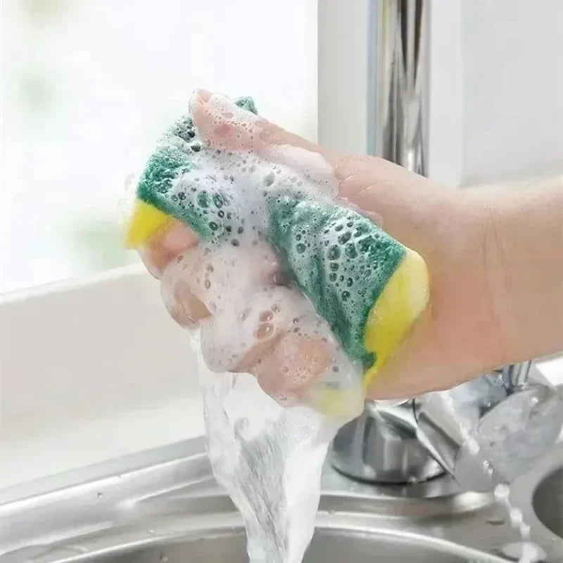 Hand holding a soapy sponge over a sink