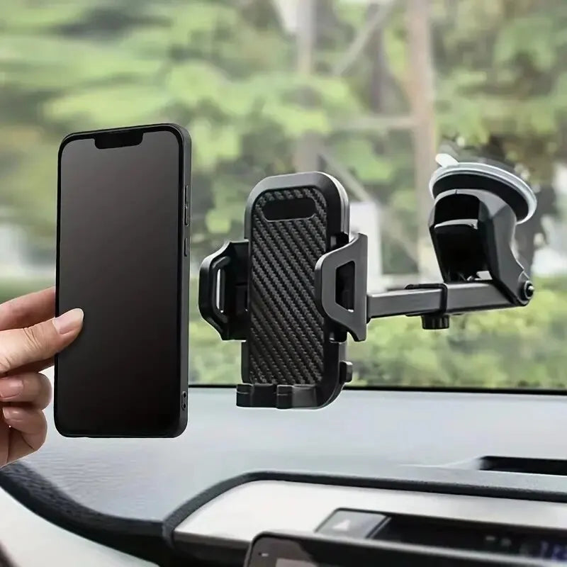 Phone holder on car dashboard with phone held by hand, blurred greenery outside window
