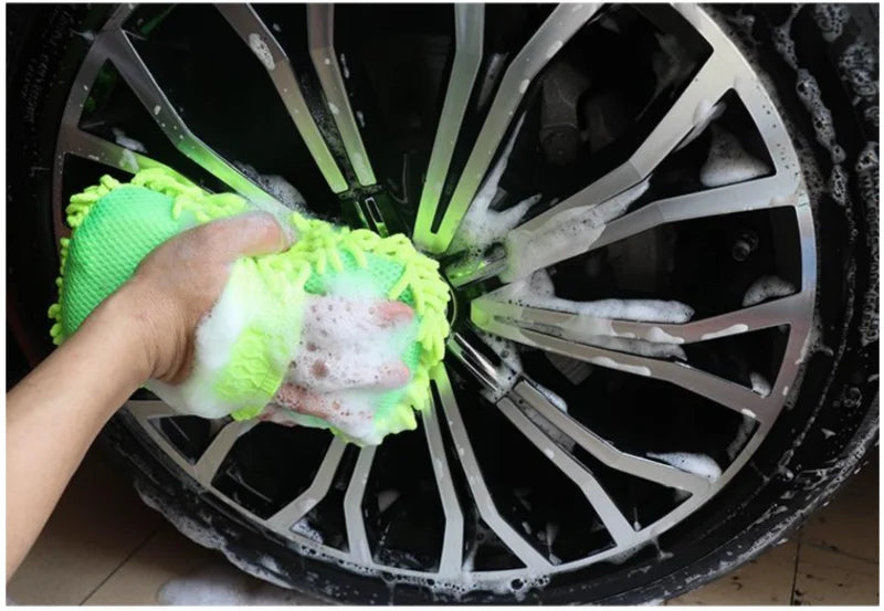 Person cleaning a car wheel with a green sponge
