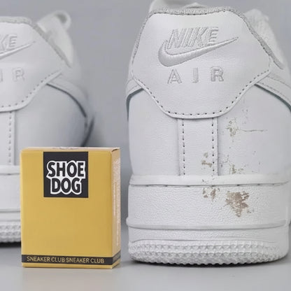 White Nike Air shoes with visible dirt, next to a yellow 'Shoe Dog' box on a gray background.