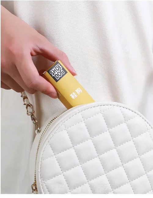 Hand holding a yellow product next to a white quilted bag